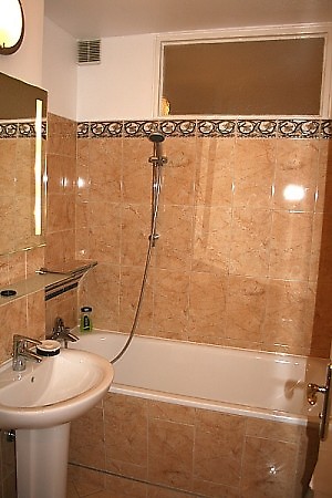 Das neu geflieste Bad – verfügt über eine Badewanne, Duschbrause, Waschbecken, Spiegel und WC