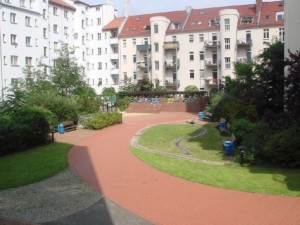 Begrünter Innenhof mit Kinderspielplatz u sprudelnder Quelle